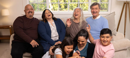 A family sits on the sofa together, talking and laughing.