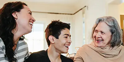 Older adult, child, and caregiver sharing a joyful moment at home reflecting intergenerational support in Alzheimer’s dementia care.