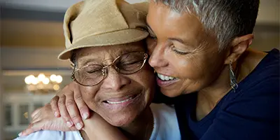 Two people embracing warmly indoors, expressing emotional connection and care in Alzheimer’s dementia support.