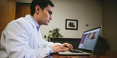 An Alzheimer's researcher in lab coat applying for a grant on a computer
