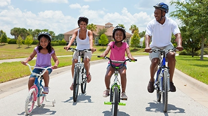 Family riding bikes and wearing helmets.