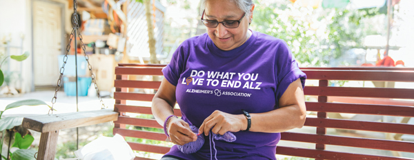 Woman knitting, wearing Do What You Love to End ALZ shirt