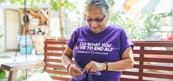 Woman knitting, wearing Do What You Love to End ALZ shirt