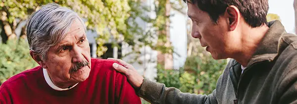 Two individuals sharing a supportive moment outdoors, reflecting emotional care and connection in Alzheimer’s dementia support.