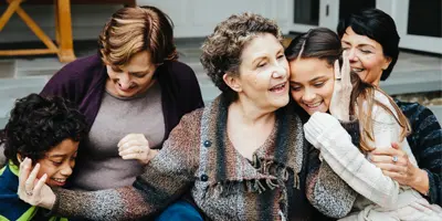 Group of five people sharing a joyful moment outdoors, representing multigenerational connection in Alzheimer’s dementia support.