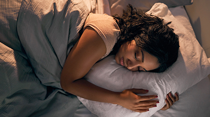 Woman sleeps in a bed with her head on a pillow.