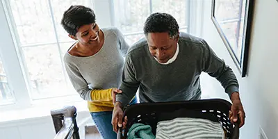 Two people on a staircase sharing a moment of support during household tasks, reflecting everyday caregiving in Alzheimer’s dementia treatment.