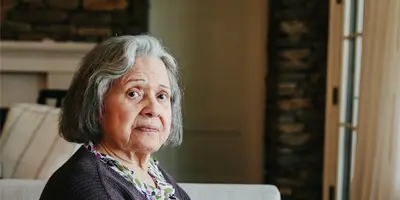 Older adult seated indoors in a cozy living space, reflecting moments of calm and dignity in Alzheimer’s dementia support.