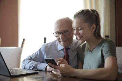 Elderly man and young woman on phone and laptop