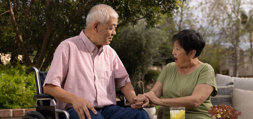 A Caregiver communicates with a person living with Alzheimer's in a wheelchair