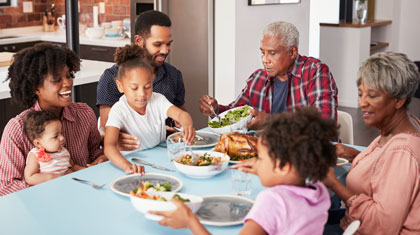 An intergenerational family eats a turkey dinner together around the table.