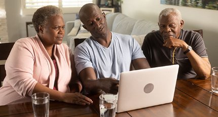 A man uses a laptop while his parents look on.