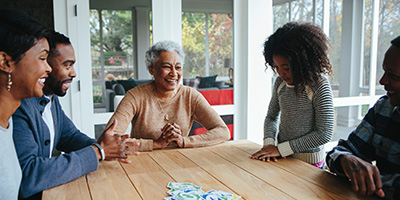 A multigenerational Black American family sits around the table smiling and laughing together.