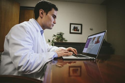 Doctor in office reading laptop