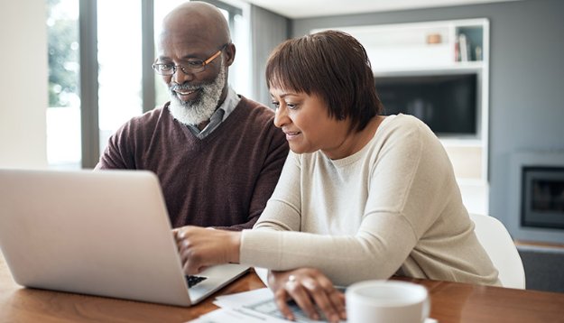 A senior couple uses a laptop computer in their home.