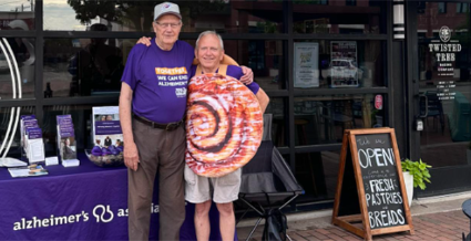 Two Edmond men staff an Alzheimer's Association table, one in cinnamon roll costume.