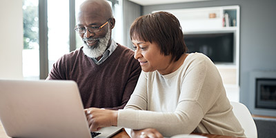 A senior couple uses a laptop.