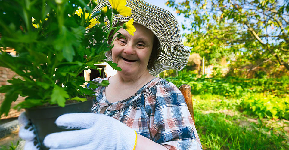 A woman with Down syndrome is gardening.