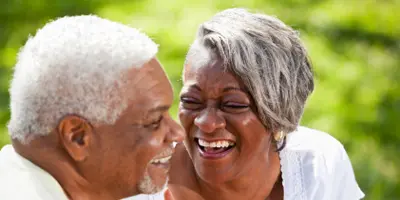 Two older adults smiling together outdoors, reflecting joyful connection in Alzheimer’s dementia support.
