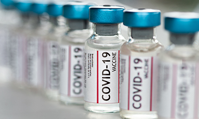 Several vials of the COVID-19 vaccine are lined up on a table.