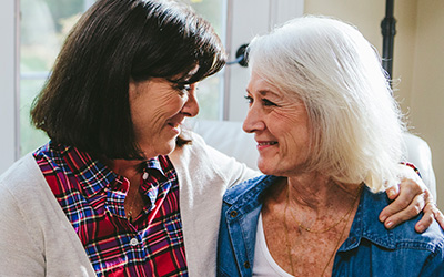 Younger and older woman smiling affectionately at one another