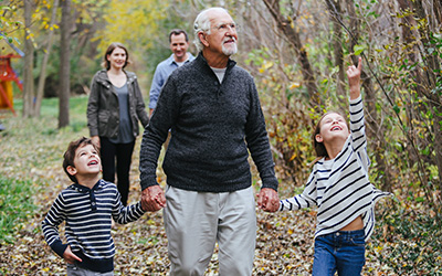 Family taking a walk in the woods, grandfather holding grandchildren's hands
