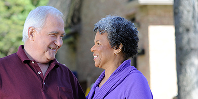 Older Black woman and older White man smiling affectionate at one another