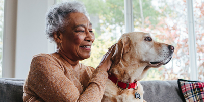 Older Black woman petting a large dog