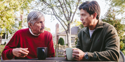 An older man having coffee with a younger man