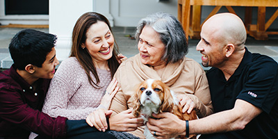 Family smiling and gathered around an older woman who is holding a spaniel puppy.